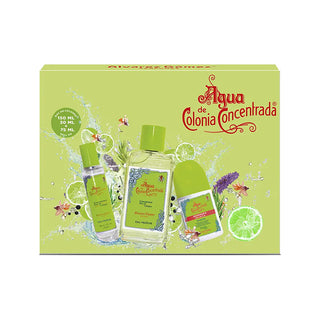 Três frascos de ‘Agua de Colonia Concentrada’ da Alvarez Gomez em tamanhos diferentes (150 ML, 30 ML, 75 ML) exibidos contra um fundo verde com respingos de água e elementos florais.